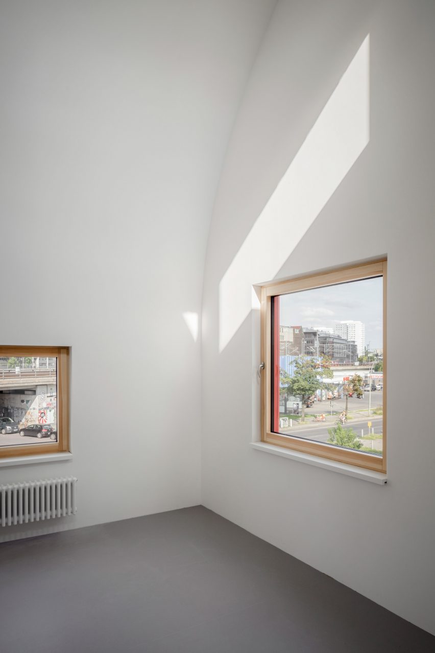 Белая комната с окнами в деревянных рамах и изогнутым потолком