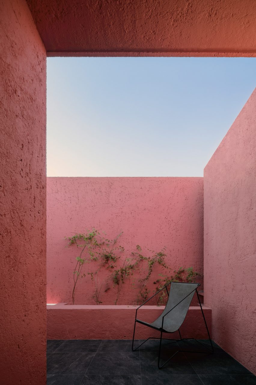 Закрытый балкон с розовыми стенами и одиночным черным стулом