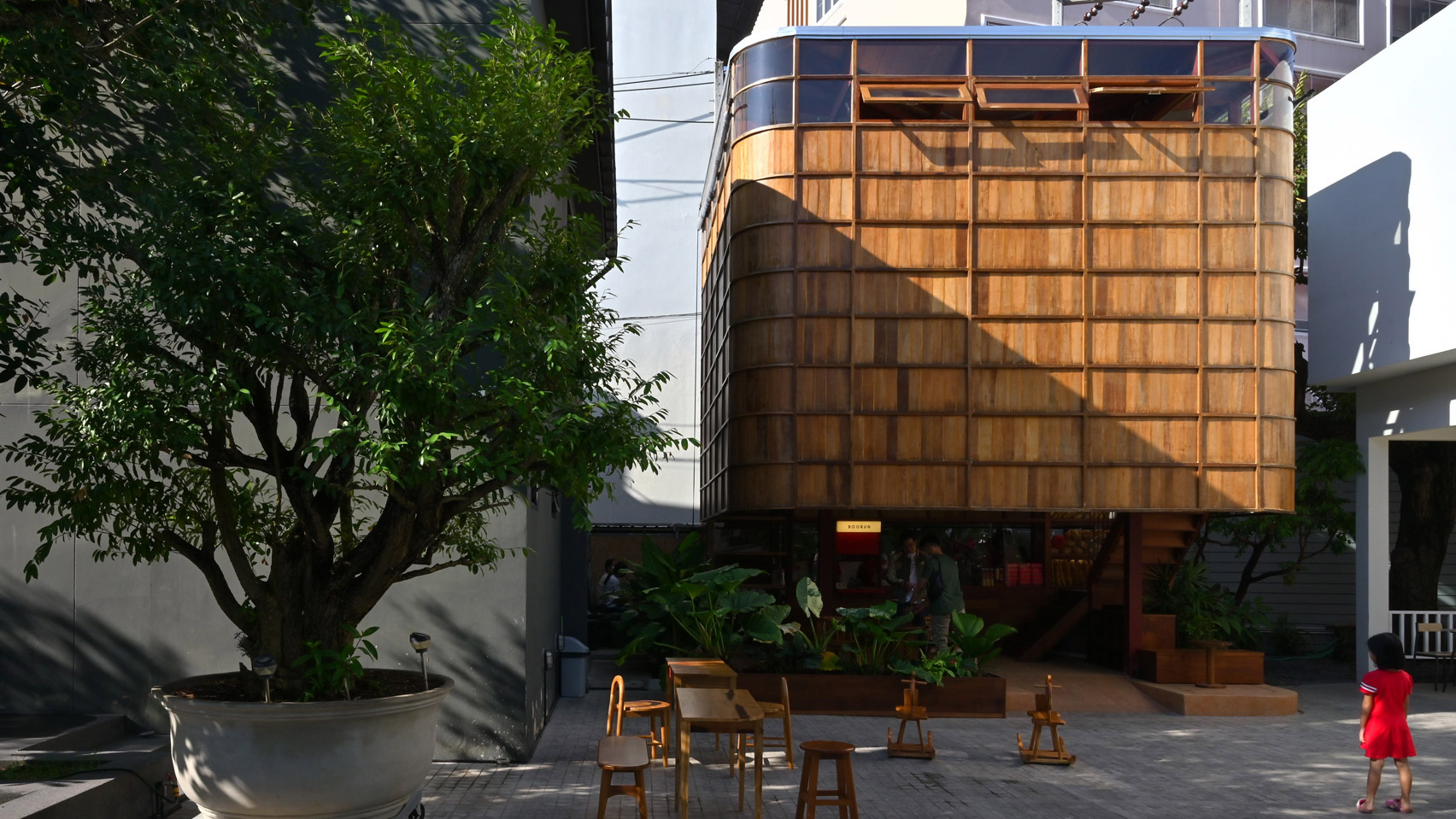 Изогнутые стены из вторичного дерева окружают карманное кафе Boobun в Таиланде.