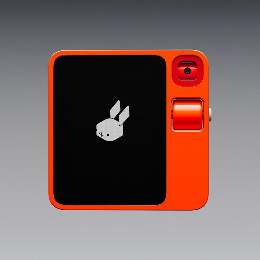 Изображение устройства Rabbit R1 спереди: ярко-оранжевый гаджет квадратной формы с экраном слева и объективом камеры и кнопкой прокрутки справа.