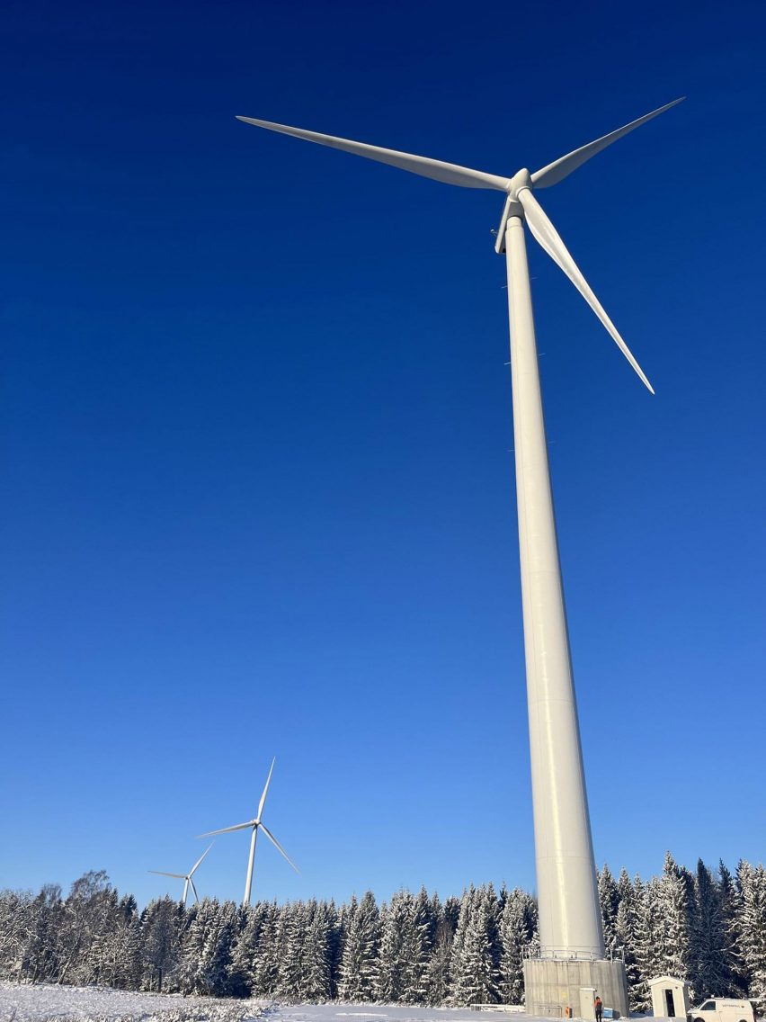 Портретная фотография высокой ветряной турбины на фоне ярко-голубого неба