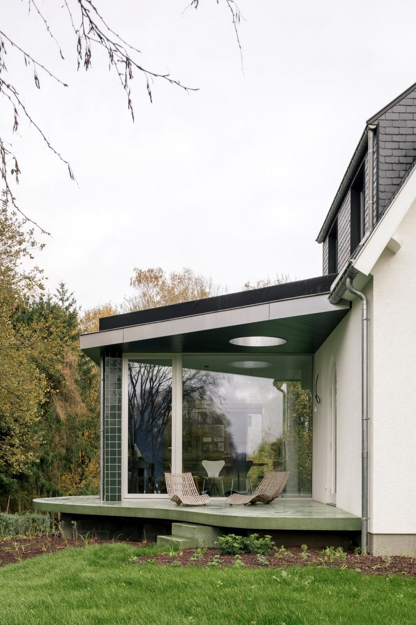 Пристройка дома, облицованная зеленой плиткой, на бетонной террасе