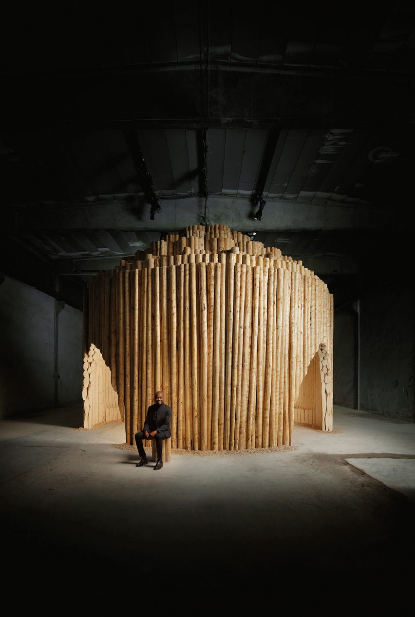 Дьебедо Франсис Кере сидел перед деревянным павильоном на неделе дизайна в Милане