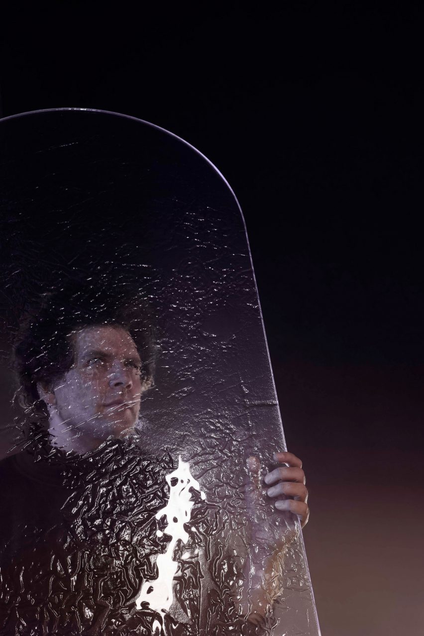 Максим Вельковский держит большую панель из плавленого стекла с фактурной отделкой. 