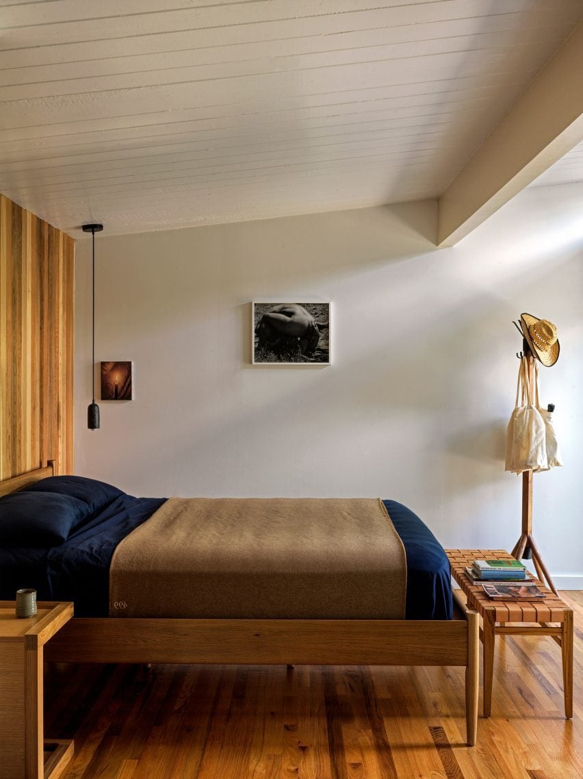 Спальня с выкрашенными в белый цвет стенами, потолками и балками, а также деревянной мебелью.
