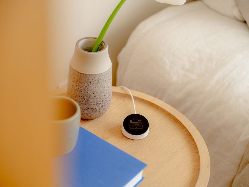 Фотография Quilt Dial, небольшого круглого устройства, стоящего на деревянном столике.