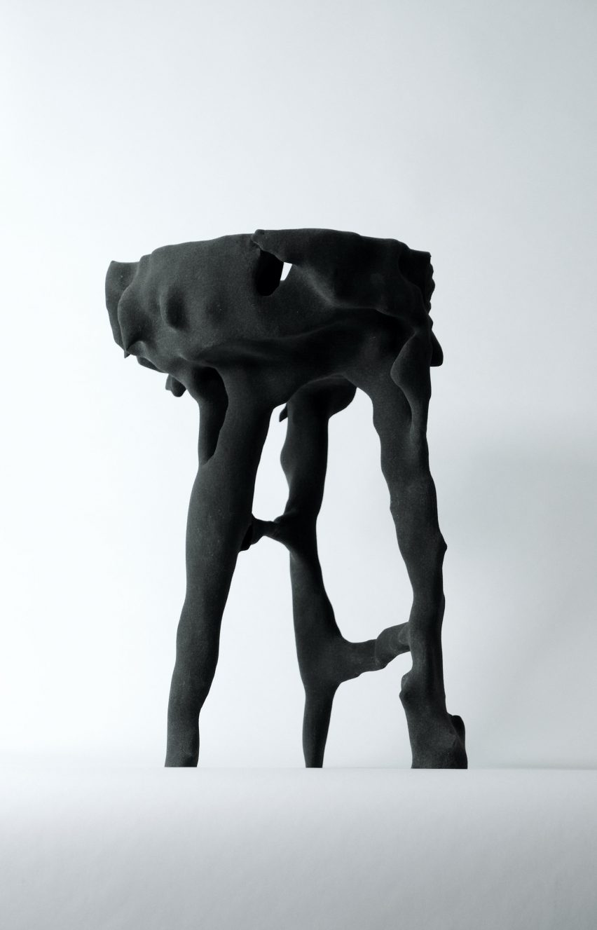 Фотография корявого табурета на трех ножках сложной формы из матового черного материала.