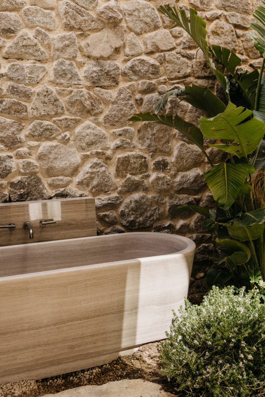 Открытая ванна у каменной стены и растений