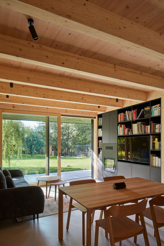 Дом в стиле хижины / Atelier Hajný - Фотография интерьера, гостиная, стол, стеллажи, окна, балка