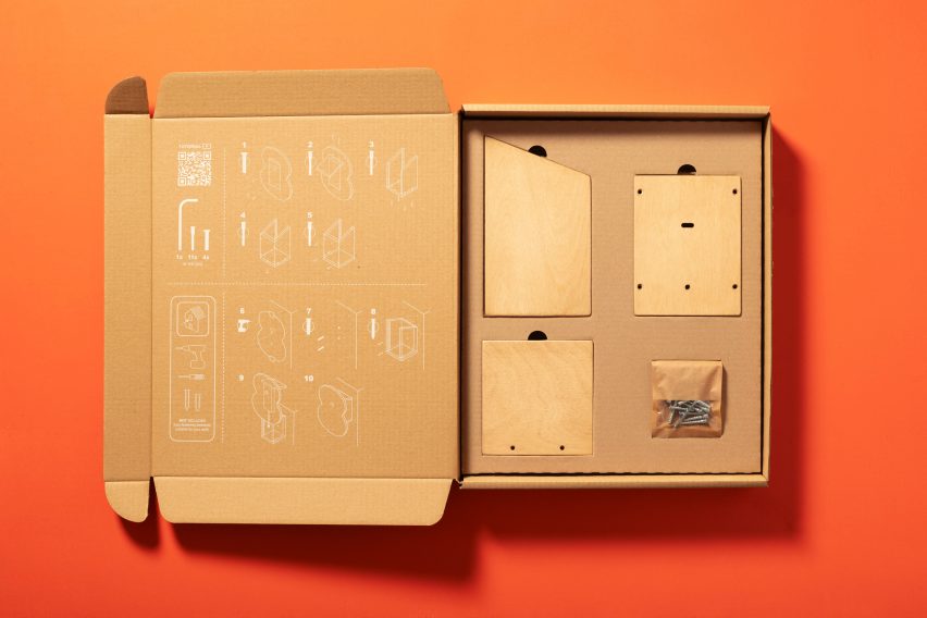 Фотография открытой картонной коробки с кусочками дерева внутри, лежащей на оранжевом фоне.