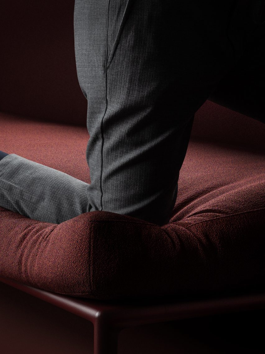 Фотография крупным планом человека, стоящего на коленях на темно-бордовом диване, колено глубоко погружается в подушку.